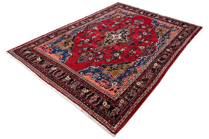 Oriental rug laid flat, red pattern with a blue ornamental border and dark edging