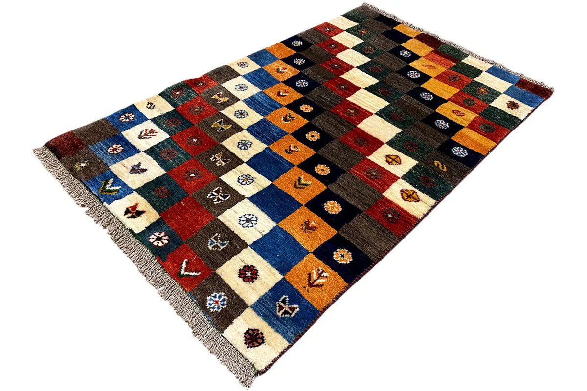 Gabbeh Lori rug at an angle with multicolored squares and fringes on the sides