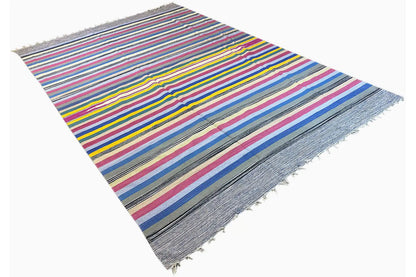 Kilim dhurrie rug in angled view with colorful stripes and a frayed edge