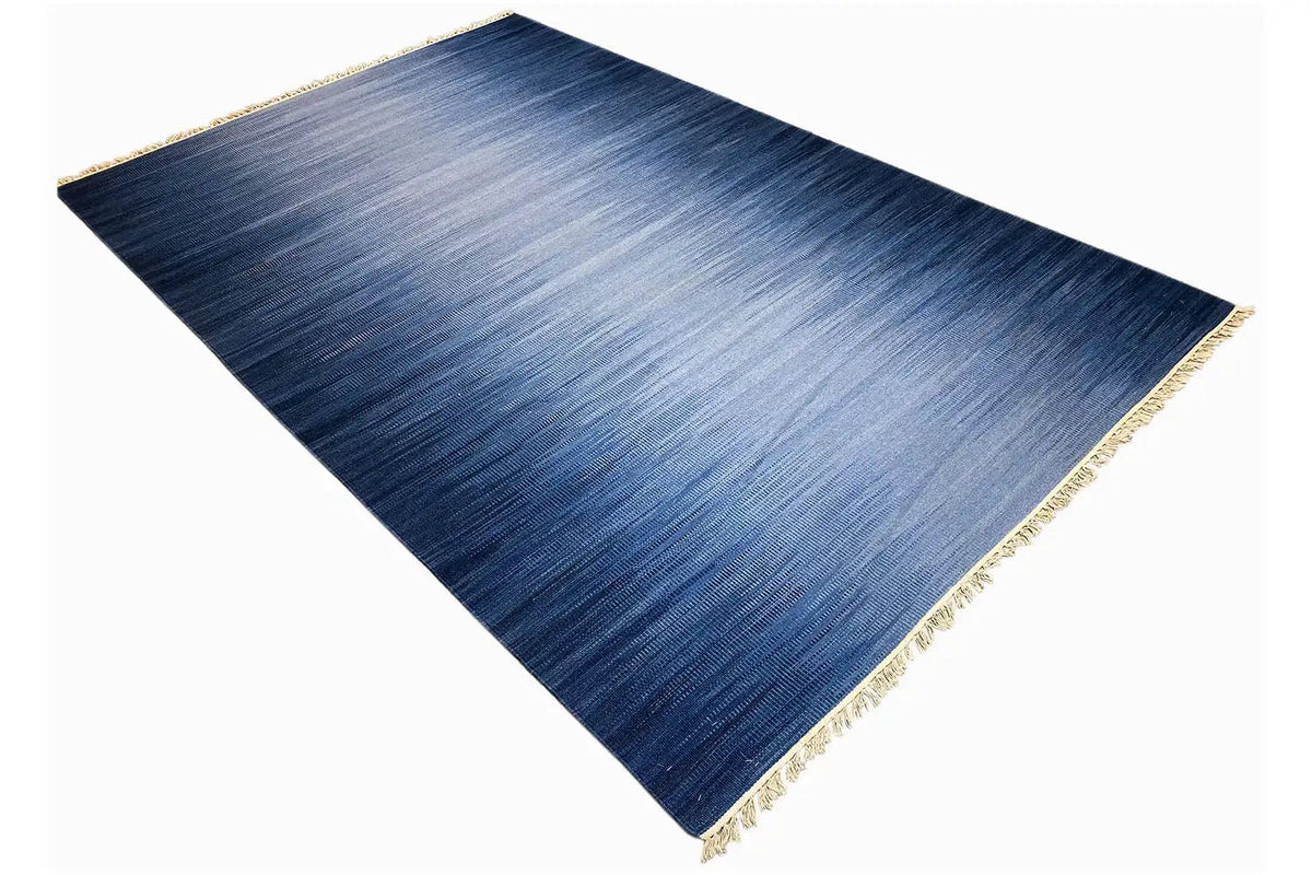 Blue kilim dhurrie rug with diagonal draping, gold-colored border and fringes