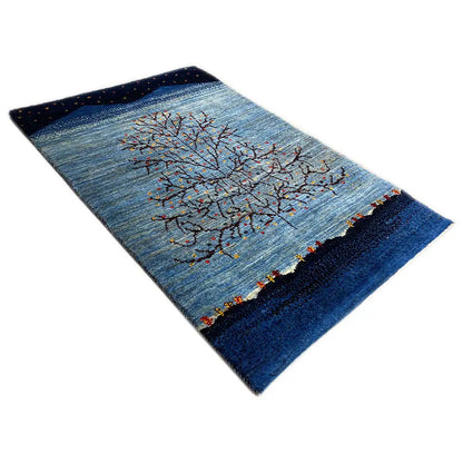 Gabbeh rug viewed diagonally: blue with a central tree motif and dark border