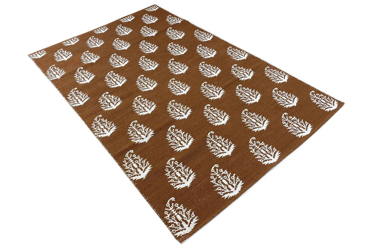 Brown kilim with white tree and floral motifs, rug surface shown diagonally