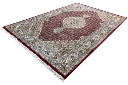 Indo-Tabriz rug at an angle, beige patterned field with a brown center and decorative border