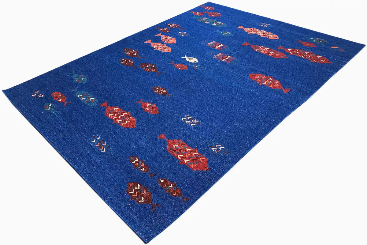 Blue kilim rug viewed from above at an angle with red and turquoise patterns