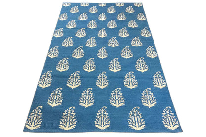 Blue A-shaped kilim rug with repeated tree/branch motifs in cream.