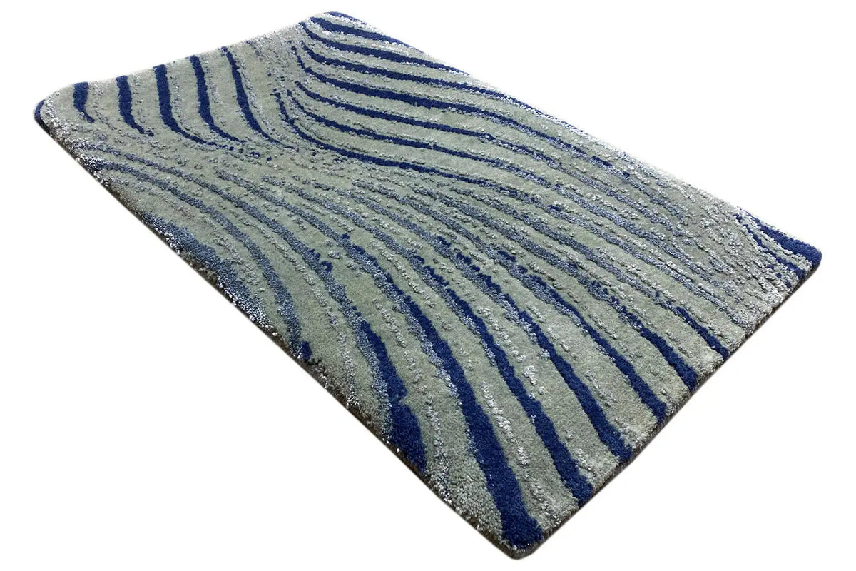 Designer rug corner with a light gray base and dark blue wavy stripes, triangular