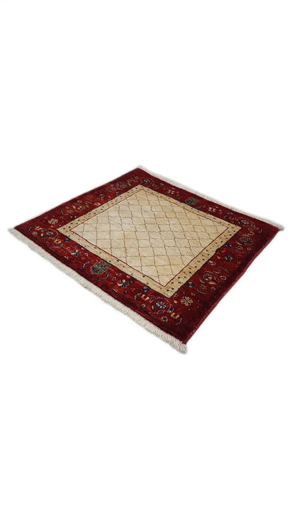 Square rug with a red ornamental border, beige central field, and fringes
