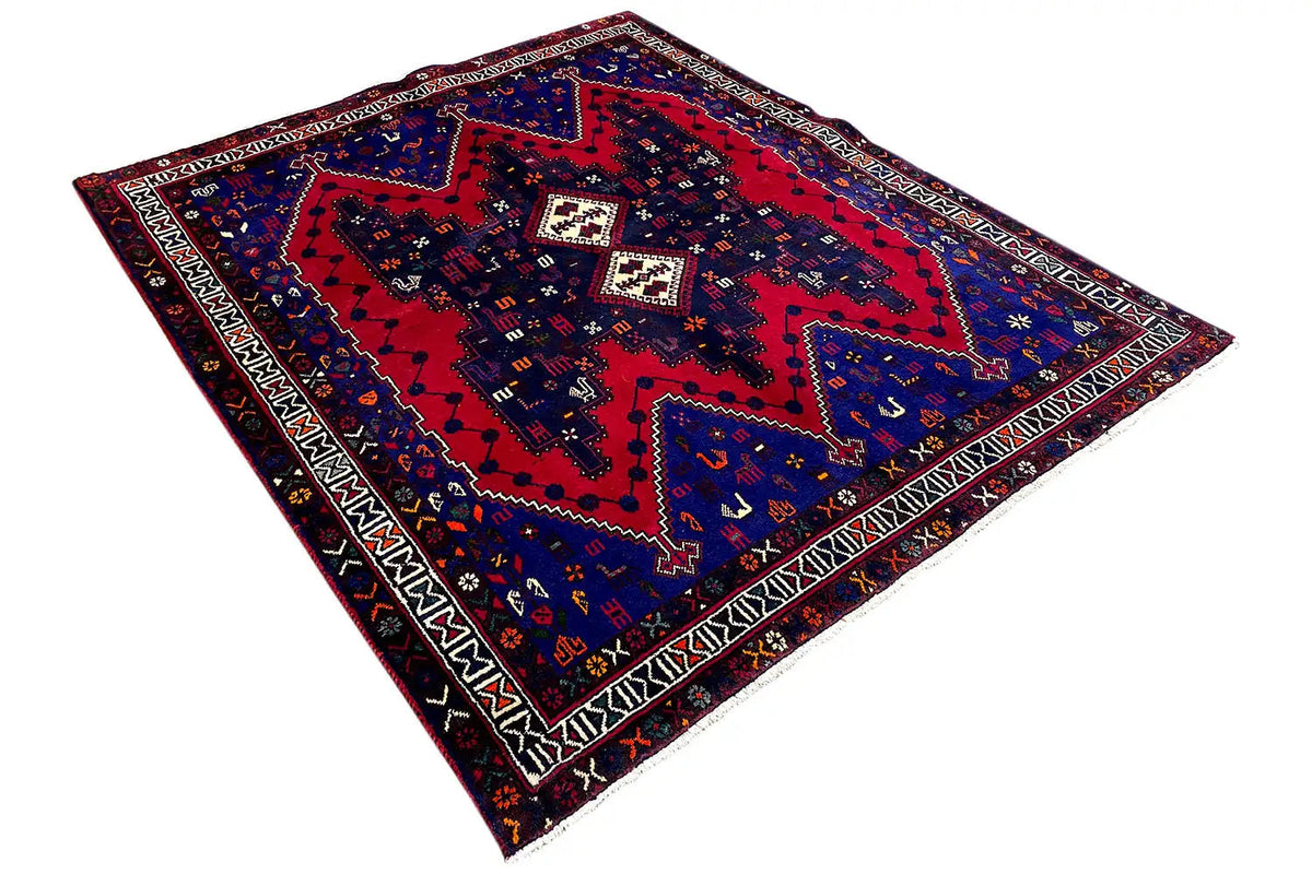Rug lying at an angle with a red central motif, borders, and geometric shapes
