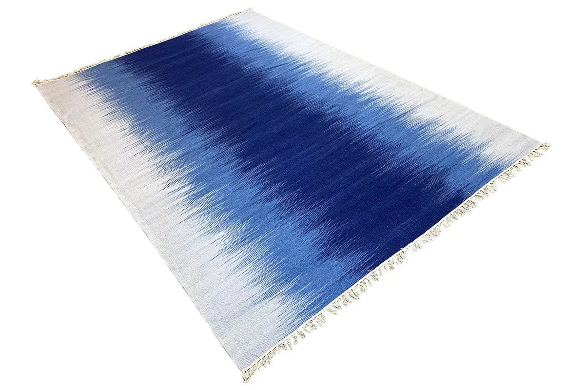 Triangular view of a light beige-blue Kelim dhurrie rug with fringes