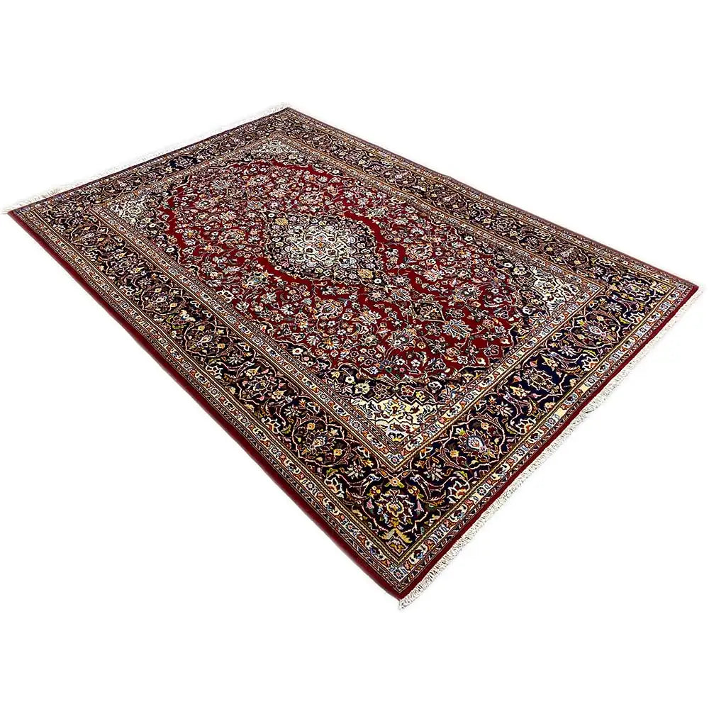 Keshan rug with a red background, delicate medallion, and dark border.