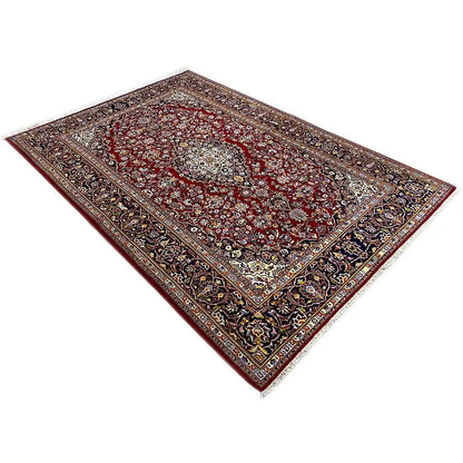 Keshan rug with a red background, delicate medallion, and dark border.