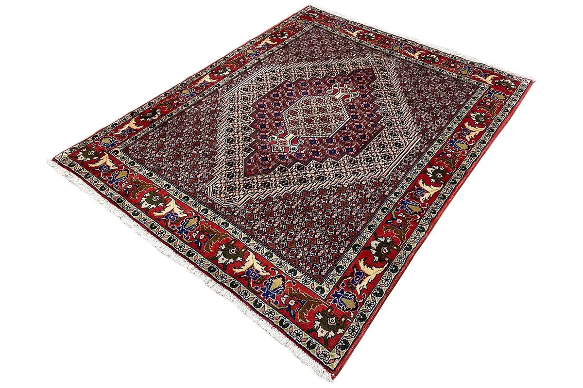 Dark red rug with a centered medallion and fine ornamental border, diagonal view