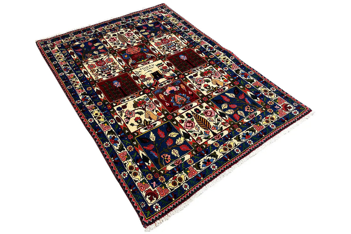 Rug in an angled view: multicolored squares with ornaments and a surrounding border.