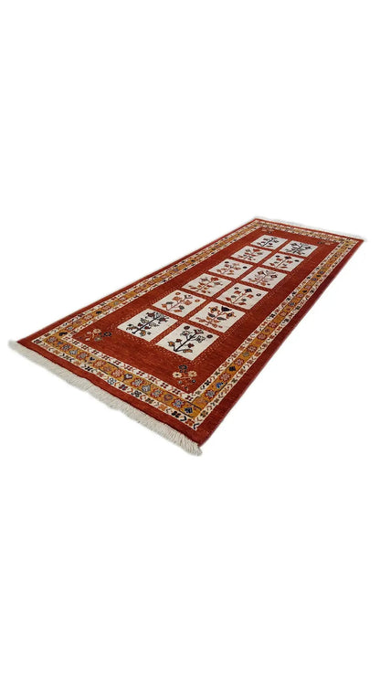 Reddish-brown oriental rug with a geometric tiled pattern, lying at an angle.