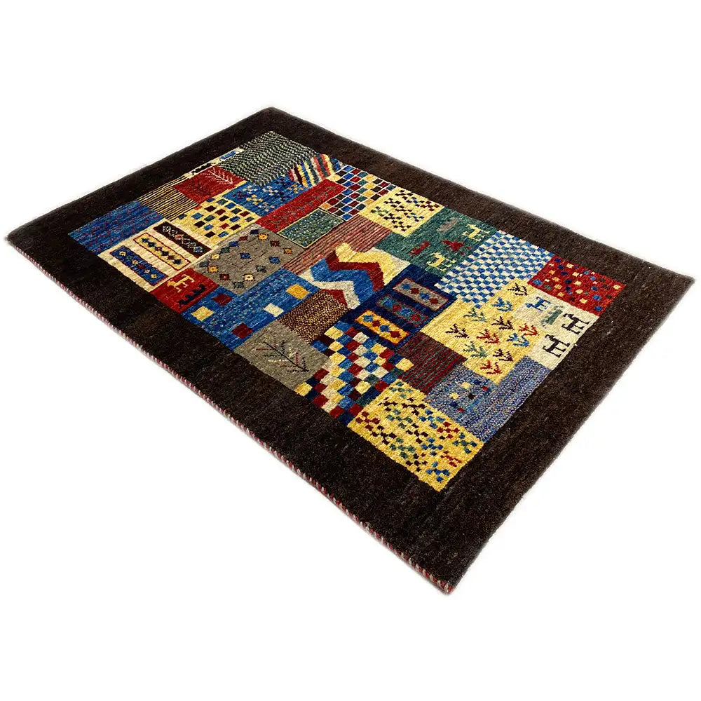 Gabbeh rug, patchwork design in blue, red, and yellow on a dark background