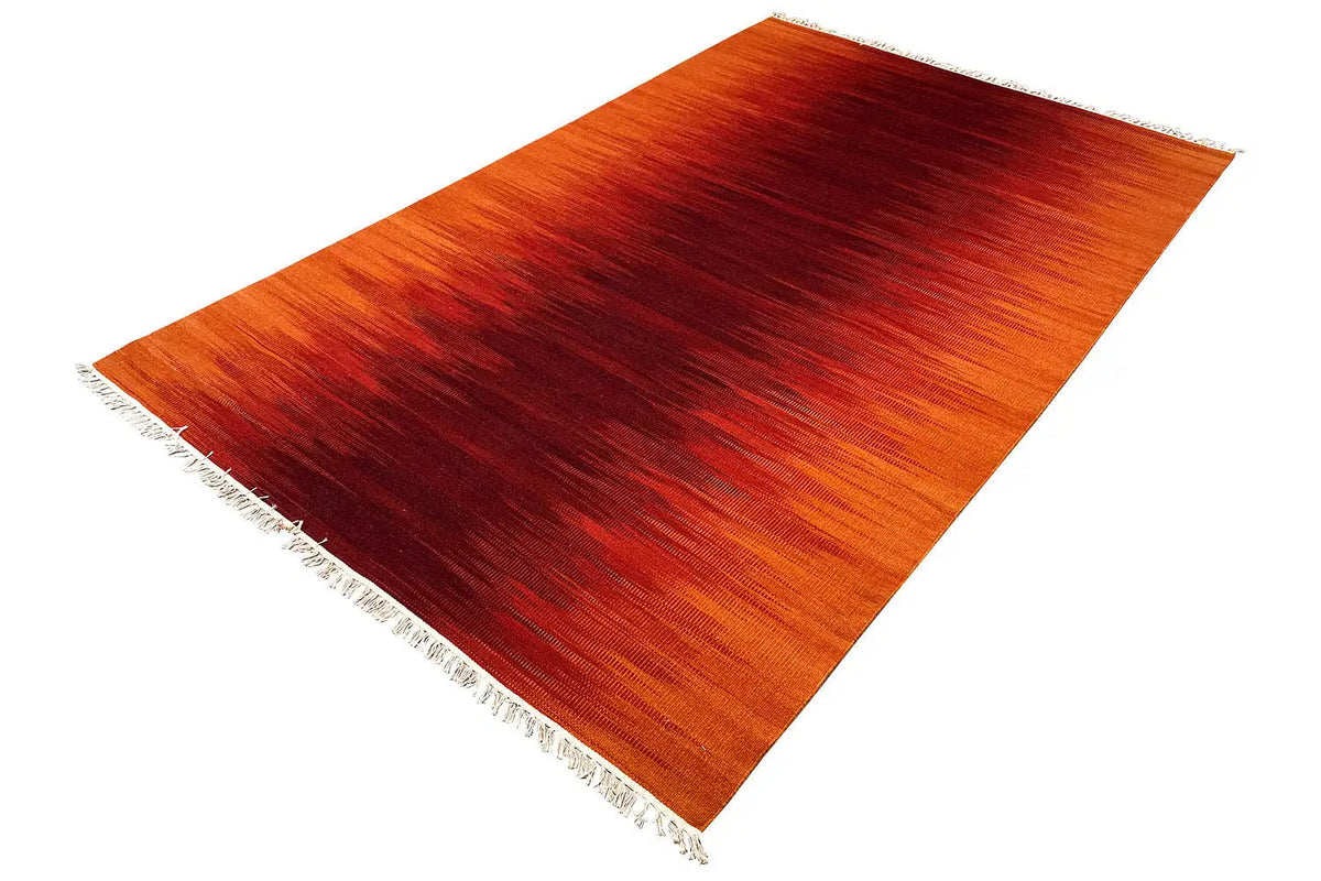 Kilim dhurrie rug, orange-red color gradients, fringe visible at the corner