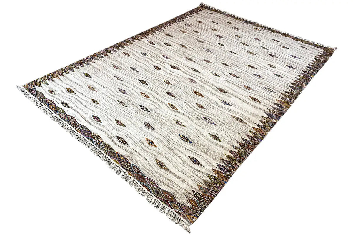 Kelim dhurrie rug shown at an angle, cream-colored with diamonds and a decorative border
