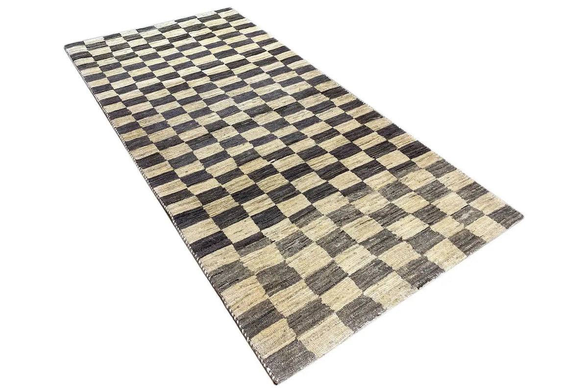 Rectangular Gabbeh rug, checkered pattern in black/brown, beige and gray, angled view