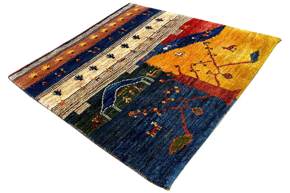 Gabbeh Lori rug at an angle with a yellow central motif and blue field