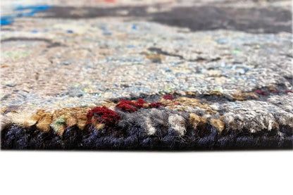 Close-up of a designer rug: multi-colored mottled pile, blue-gray with red accents.