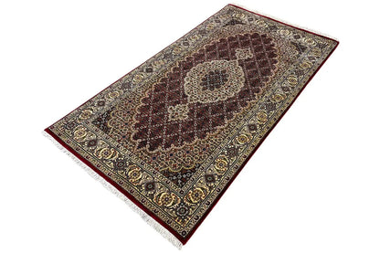 Rug shown at an angle with a central medallion, decorative border, and fringe