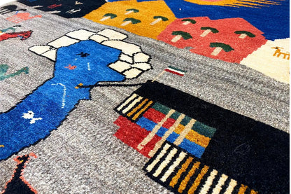 Close-up of a Gabbeh rug: gray field with a blue motif, houses, and borders