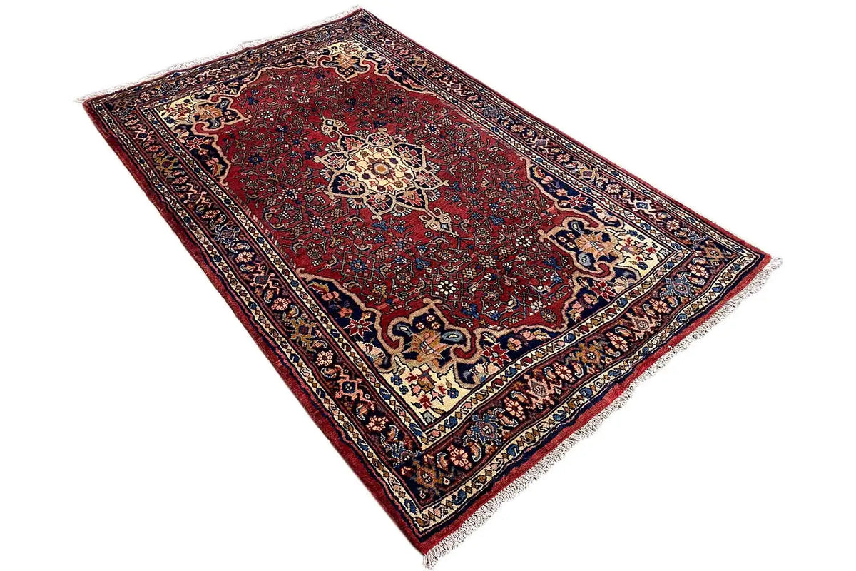Carpet with a decorative central motif, dark red, viewed from above at an angle