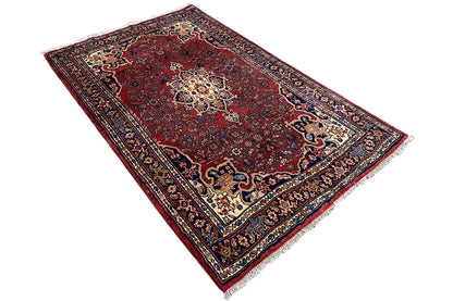 Carpet with a decorative central motif, dark red, viewed from above at an angle