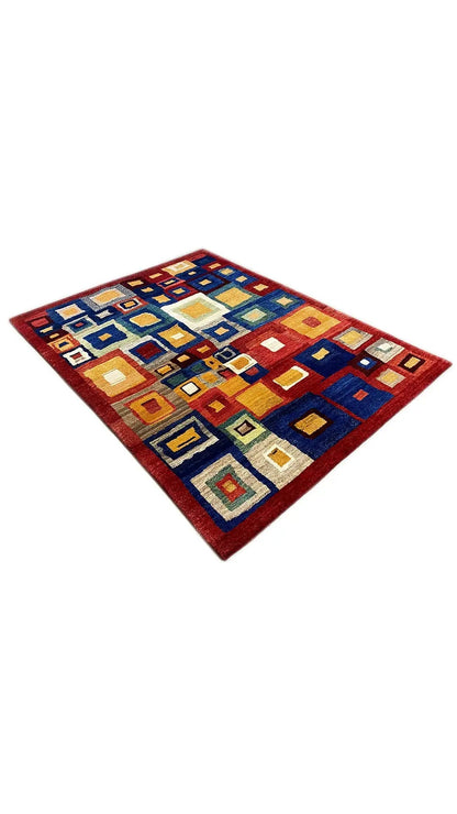 Gabbeh rug spread out with a colorful tile pattern in blue, red, and beige