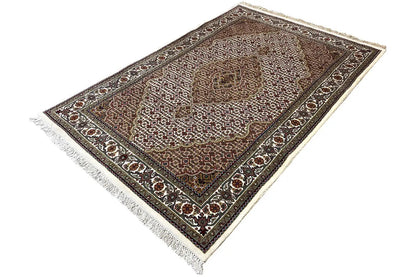 Indo Tabriz rug 181x120 cm, diagonal view with a geometric border and fringes