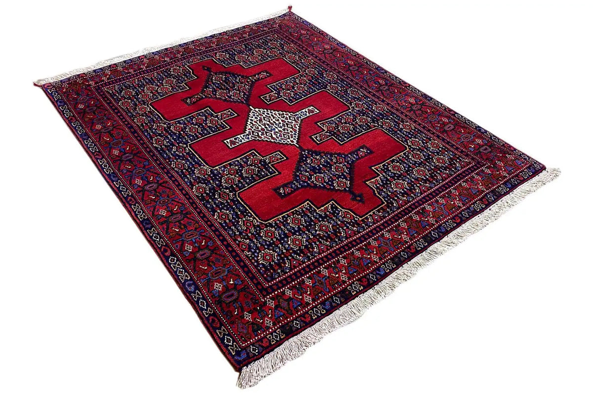 Rug at an angle: dark red and blue pattern with a central star motif, with fringes visible at the sides.