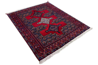 Rug at an angle: dark red and blue pattern with a central star motif, with fringes visible at the sides.