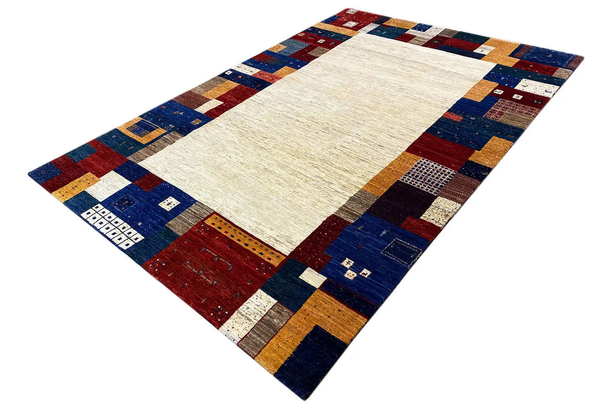 Gabbeh rug at an angle, light center with blue-red patchwork and border