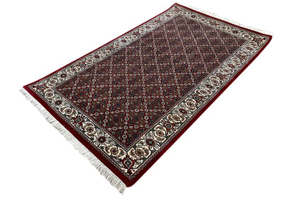 Bidjar rug at an angle: geometric ornaments, dark red with a cream-colored border trim