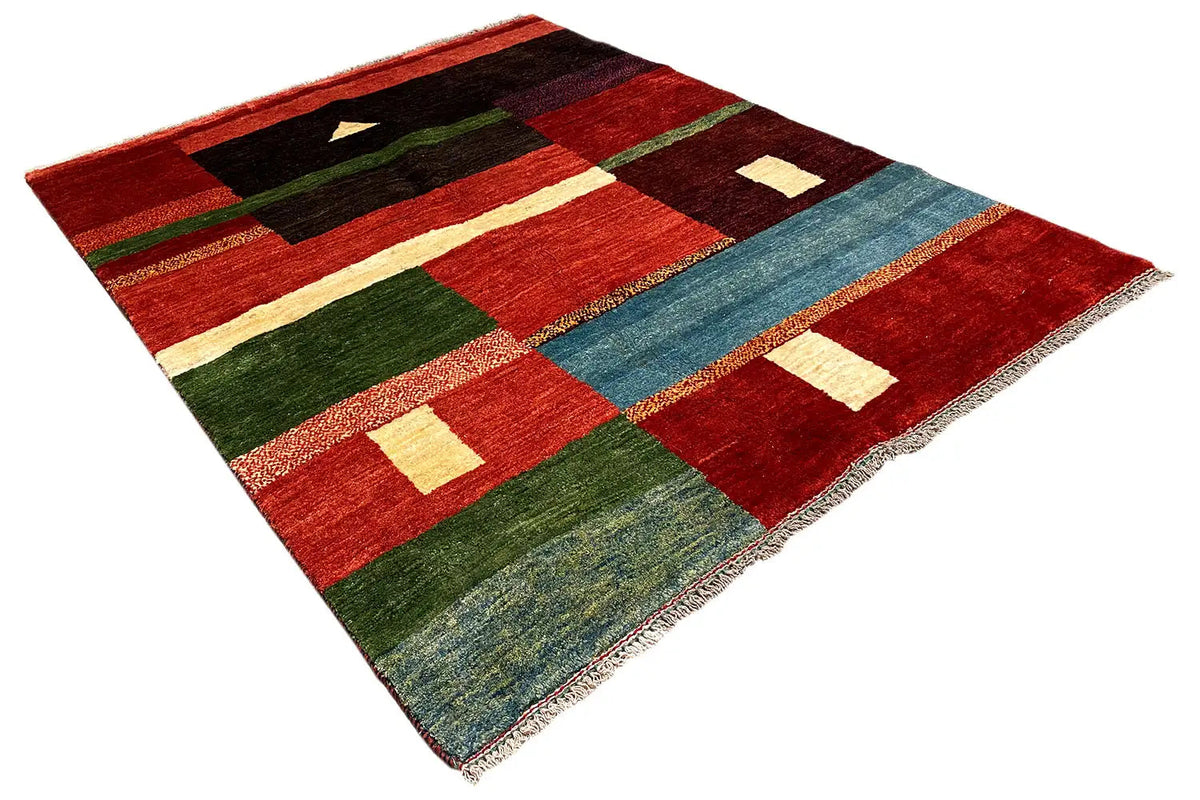 Gabbeh rug spread at an angle, geometric patterns in red, green, black, and blue