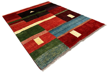 Gabbeh rug spread at an angle, geometric patterns in red, green, black, and blue