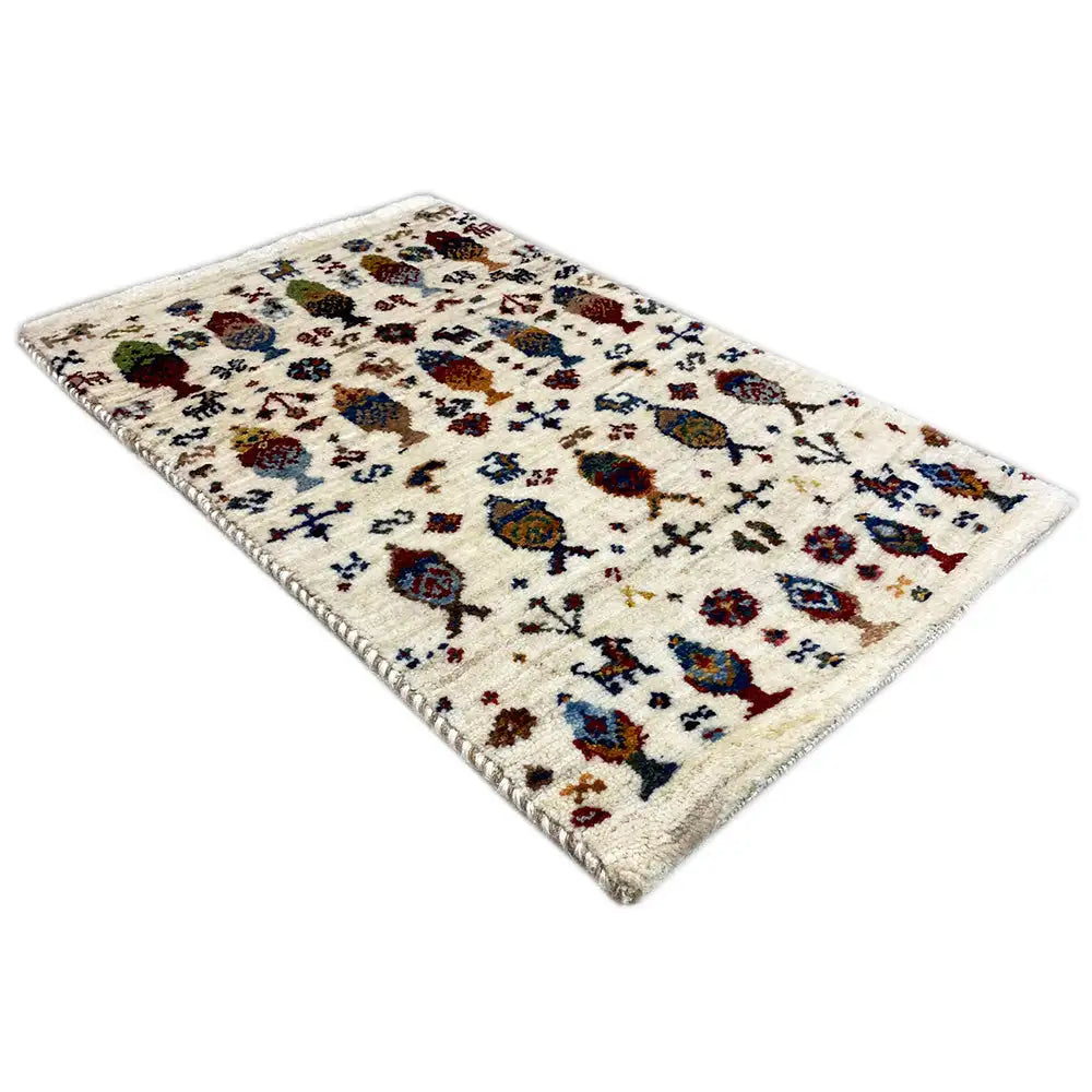 Gabbeh rug 58x37 cm shown at an angle, cream with colorful figures and ornaments.