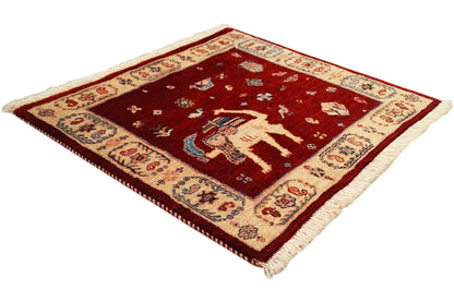 Square rug with a red ground, central motif, and wide patterned border