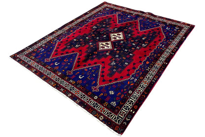 Rug at an angle: blue field with red pattern, white accents, and decorative border