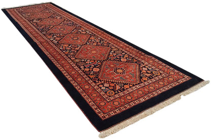 Oriental rug runner in red and dark blue with a geometric medallion pattern, fringes on both ends