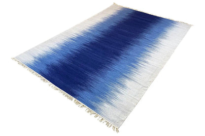 Kilim dhurrie rug with a blue pattern in the center and light-colored borders
