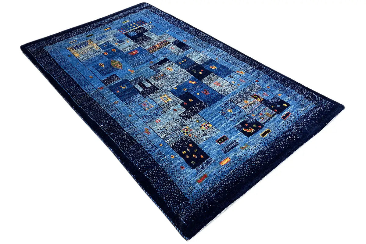Gabbeh rug, photographed at an angle: blue patchwork with multicolored details