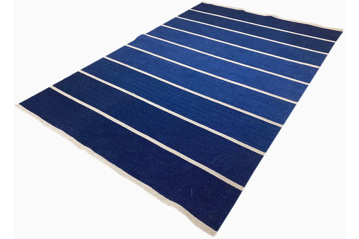 Kilim rug with a dark blue background and light horizontal stripes, folded slightly diagonally.