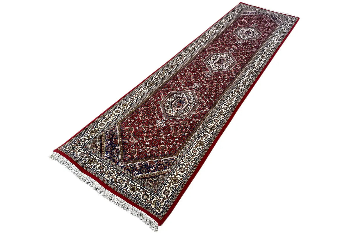 Bidjar runner with a burgundy patterned field and ornate border, fringes at the bottom.