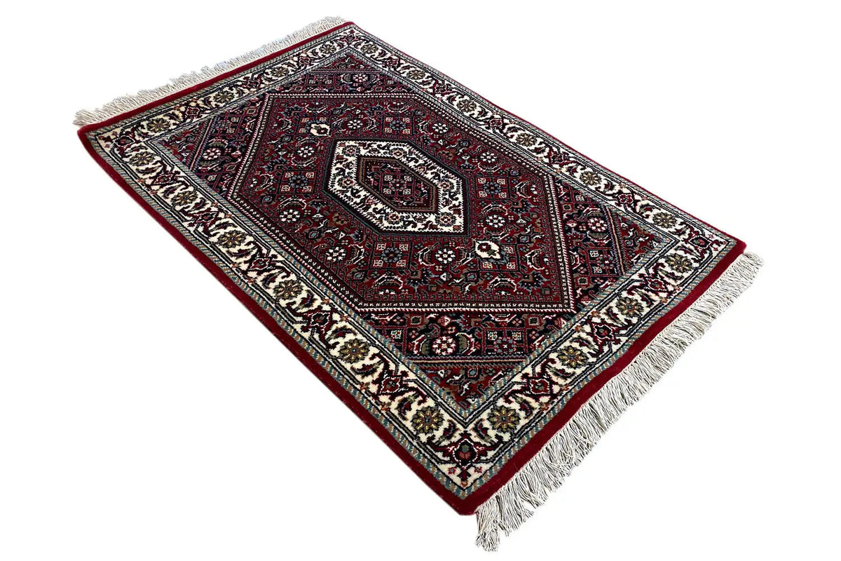Carpet laid diagonally, red pattern with central medallion, cream border, fringes