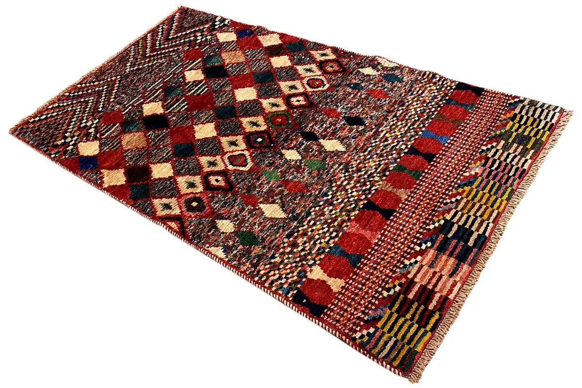 Rug spread at an angle with a geometric pattern and multicolored fringed border