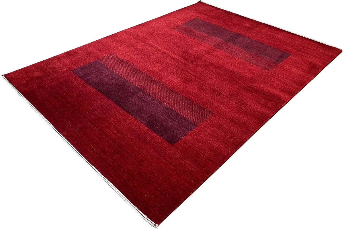 Gabbeh rug spread diagonally: wider dark patterned bands, red pile