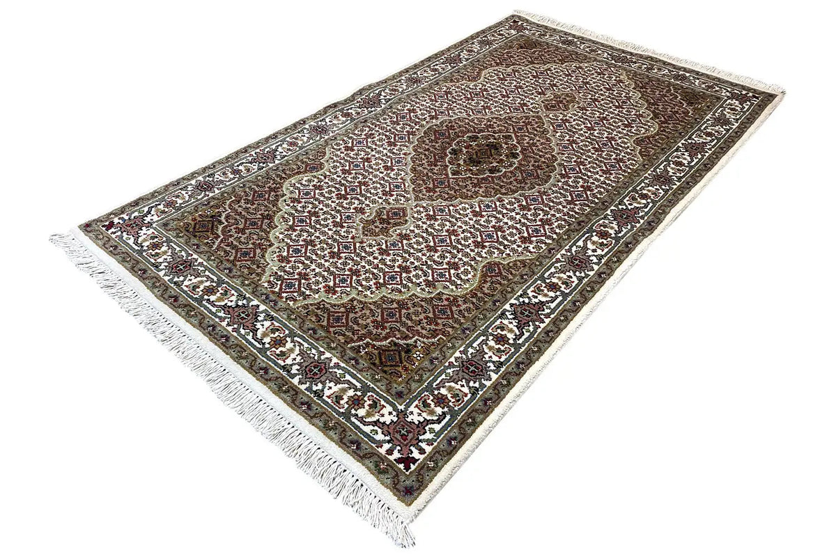 Indo Tabriz rug: front view, brown ornamental medallion, white border, fringes.