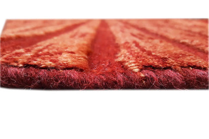 Gabbeh rug edge view: dense reddish-brown pile, with fringes
