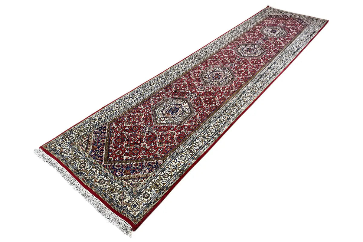 Bidjar runner with a geometric pattern and fringes in red, blue, and beige, angled